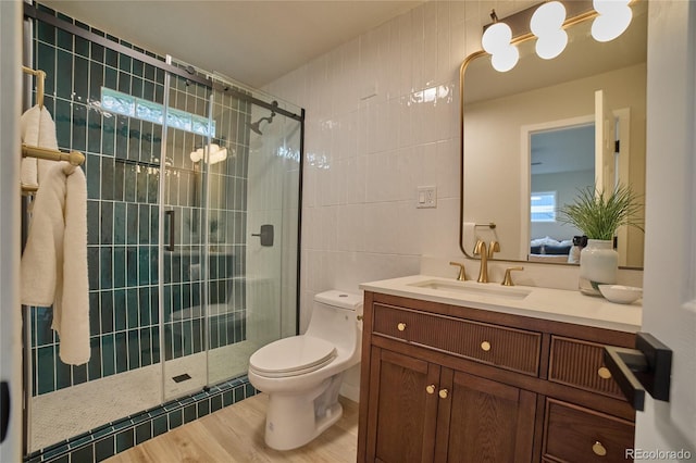 bathroom featuring vanity, an enclosed shower, wood-type flooring, tile walls, and toilet