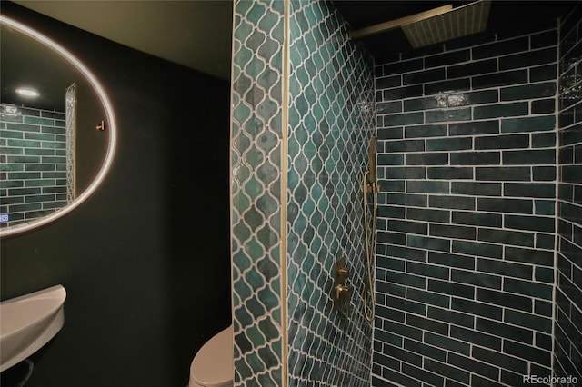 bathroom featuring tiled shower and toilet