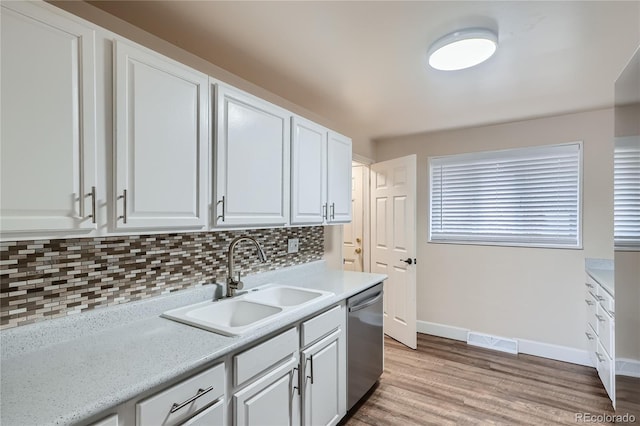 kitchen featuring sink, tasteful backsplash, light hardwood / wood-style flooring, stainless steel dishwasher, and white cabinets