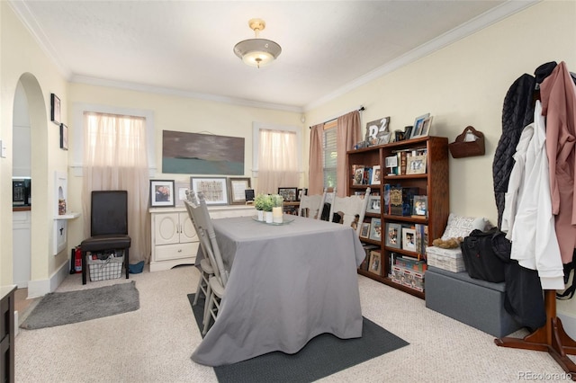 dining area with crown molding, plenty of natural light, carpet, and arched walkways