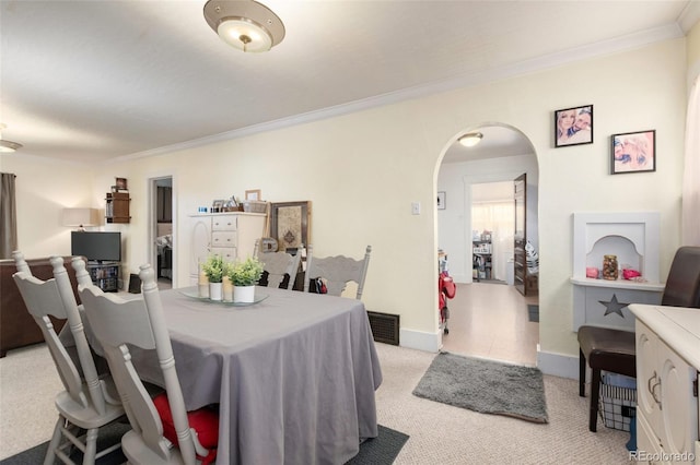 dining space with ornamental molding, arched walkways, carpet floors, and baseboards