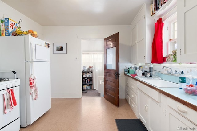 kitchen featuring white appliances, plenty of natural light, a sink, and light countertops