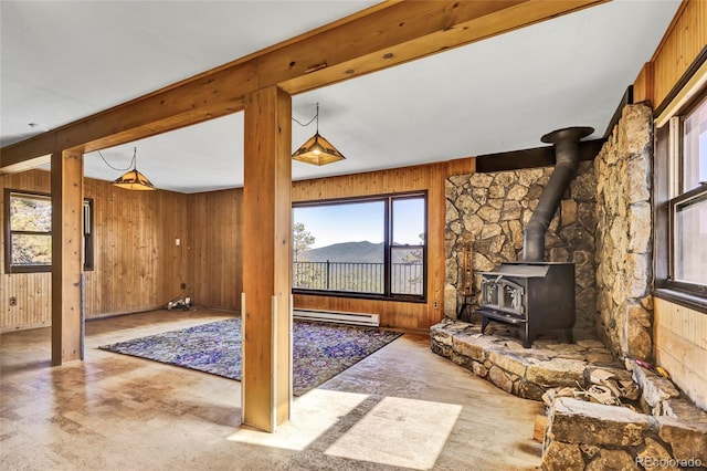 unfurnished living room with a baseboard heating unit, wood walls, a wood stove, and a mountain view