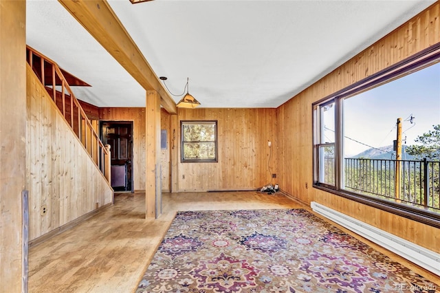 spare room with wood walls, a baseboard radiator, and a wealth of natural light