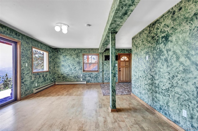 unfurnished room featuring hardwood / wood-style flooring, baseboard heating, and plenty of natural light