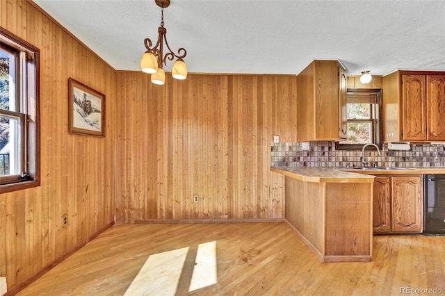 kitchen featuring pendant lighting, light hardwood / wood-style floors, backsplash, and wood walls