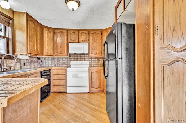 kitchen with wine cooler, sink, white appliances, light wood-type flooring, and decorative backsplash