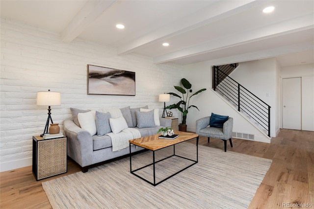 living room featuring light wood finished floors, visible vents, beamed ceiling, stairs, and recessed lighting