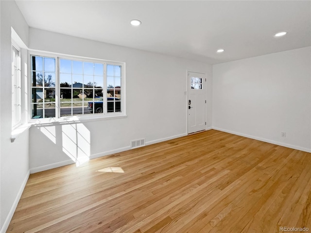 empty room with plenty of natural light and light hardwood / wood-style floors