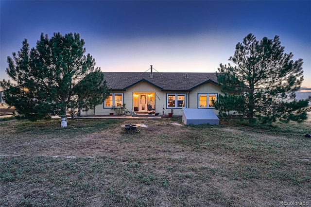 ranch-style house with a lawn and a fire pit