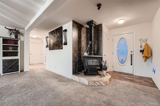 unfurnished living room featuring carpet floors, a textured ceiling, and a wood stove