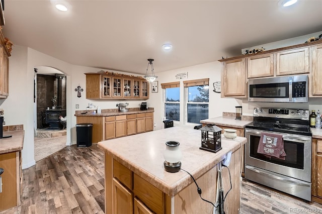 kitchen featuring a wood stove, hardwood / wood-style flooring, a kitchen island, pendant lighting, and stainless steel appliances