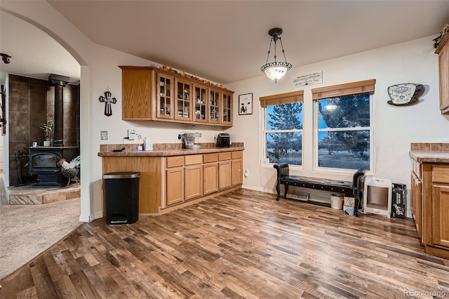 kitchen with hanging light fixtures, dark wood-type flooring, and a wood stove