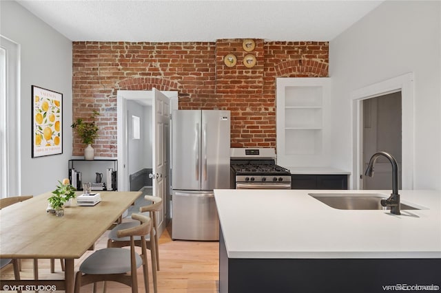 3817 Osage St, Denver, CO 80211 - kitchen with stainless steel appliances, light wood-style floors, brick wall, and light countertops