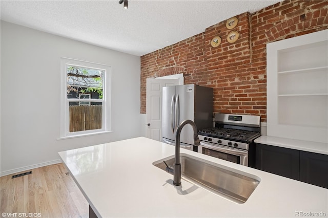 3817 Osage St, Denver, CO 80211 - kitchen featuring appliances with stainless steel finishes, a textured ceiling, dark cabinets, light countertops, and brick wall