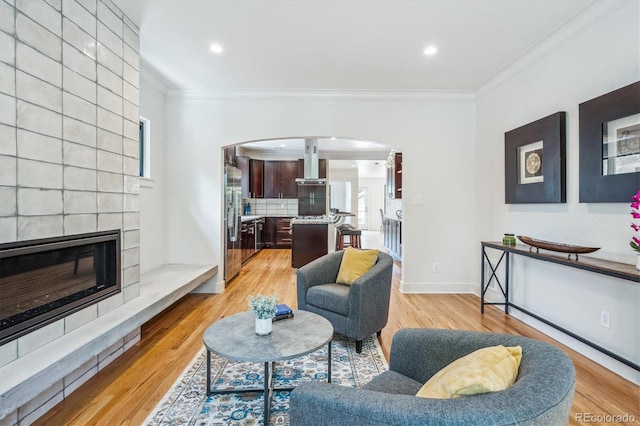 living room with plenty of natural light, a fireplace, ornamental molding, and light hardwood / wood-style flooring