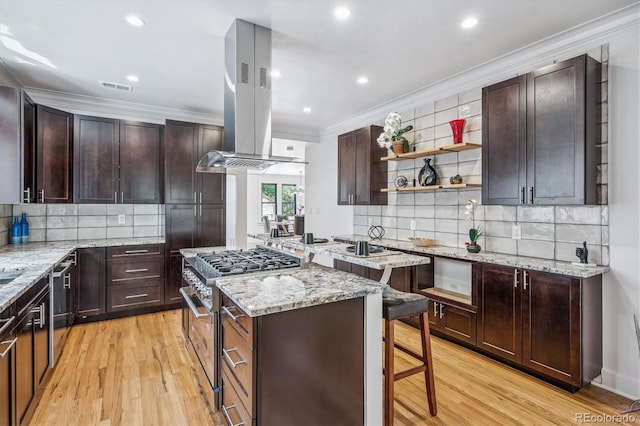 kitchen featuring stainless steel appliances, island range hood, backsplash, crown molding, and light wood-type flooring