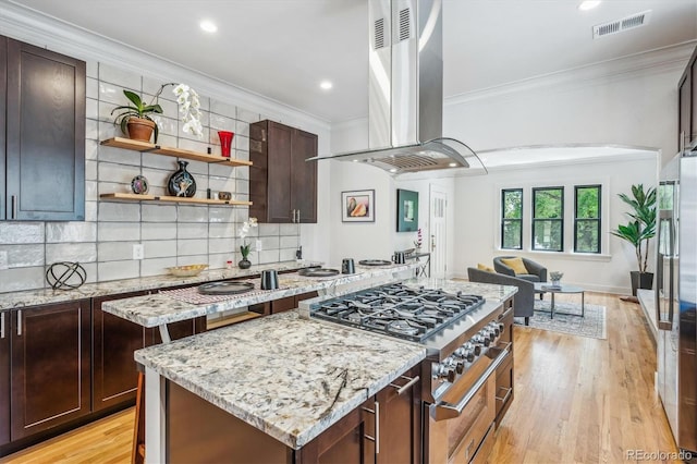 kitchen featuring island range hood, backsplash, light hardwood / wood-style floors, and light stone countertops