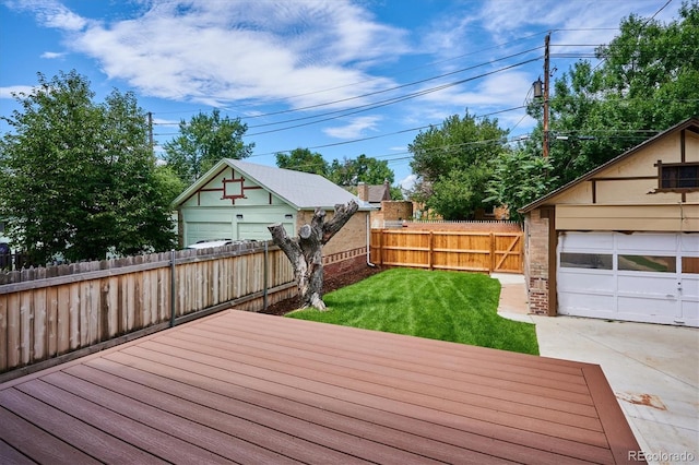 wooden terrace with a garage, a lawn, and an outbuilding