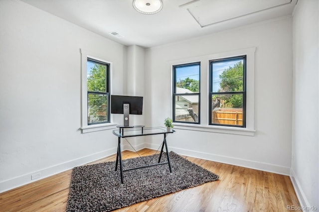 office space with wood-type flooring, a healthy amount of sunlight, and crown molding