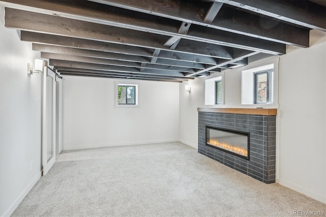 basement with a wealth of natural light, light carpet, and a tile fireplace