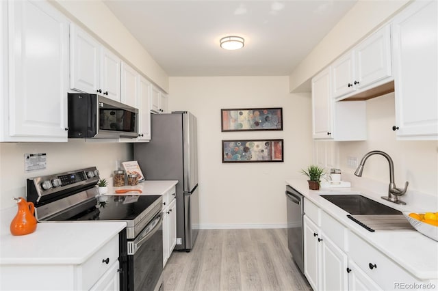 kitchen featuring appliances with stainless steel finishes, light hardwood / wood-style flooring, white cabinetry, and sink