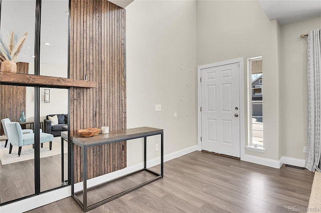 entryway with a towering ceiling, wood finished floors, visible vents, and baseboards