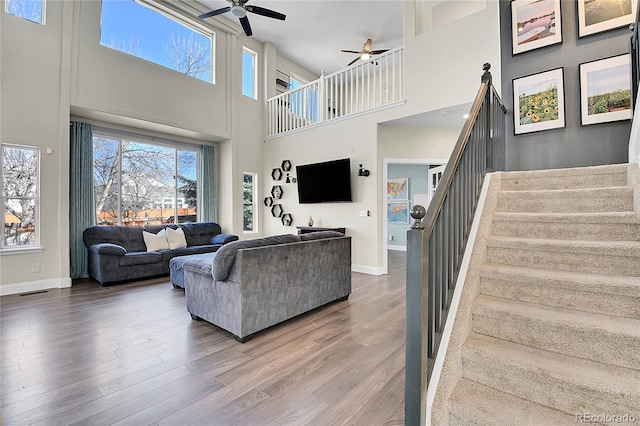 living area with plenty of natural light, stairs, ceiling fan, and wood finished floors