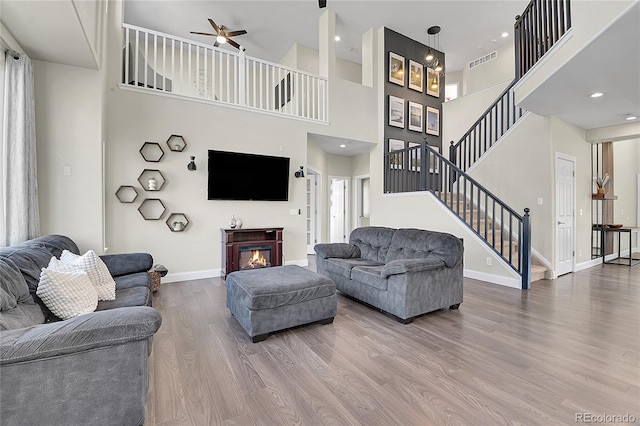 living area featuring wood finished floors, visible vents, baseboards, stairs, and a glass covered fireplace