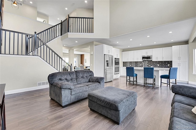 living area with dark wood-style floors, visible vents, plenty of natural light, and stairway