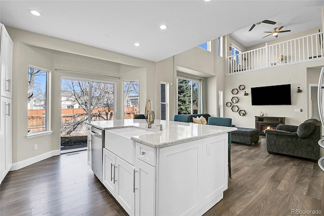 kitchen with light stone counters, dark wood-type flooring, white cabinetry, open floor plan, and dishwasher