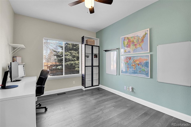 office featuring dark wood-style floors, visible vents, a ceiling fan, and baseboards