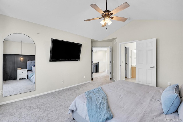 bedroom with ensuite bathroom, light carpet, a ceiling fan, baseboards, and vaulted ceiling