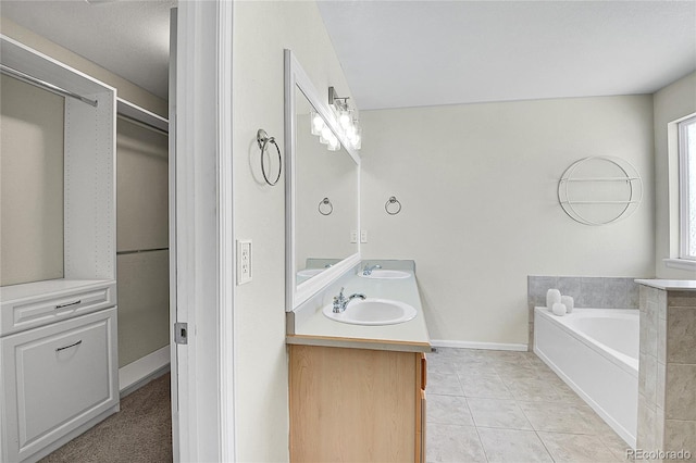 bathroom with double vanity, a sink, tile patterned flooring, baseboards, and a bath