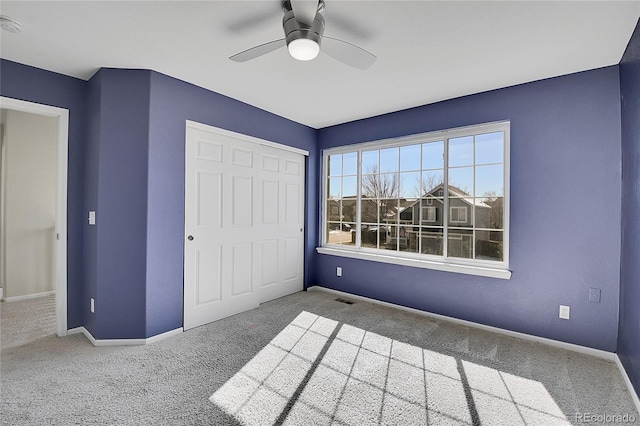 unfurnished bedroom featuring baseboards, visible vents, ceiling fan, carpet, and a closet