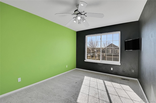 carpeted spare room featuring visible vents, baseboards, and a ceiling fan