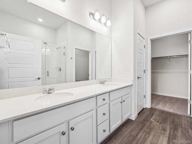 485 Interlocken Blvd Unit 101, Broomfield, CO 80021 - bathroom with a shower stall, a spacious closet, double vanity, and wood finished floors
