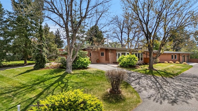 ranch-style home with a front yard, brick siding, and aphalt driveway