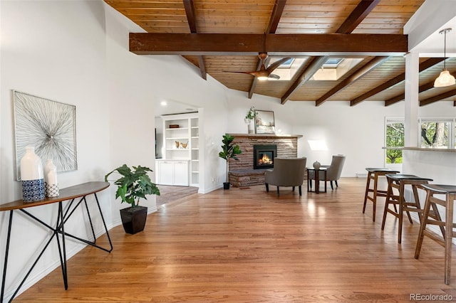 interior space with light wood-type flooring, a fireplace, vaulted ceiling with skylight, and wooden ceiling