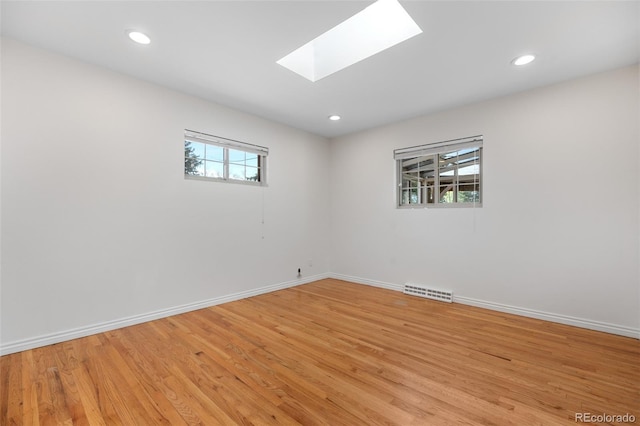 spare room with visible vents, a skylight, baseboards, light wood finished floors, and recessed lighting