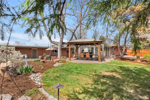 back of house featuring fence, a gazebo, brick siding, a patio area, and a lawn