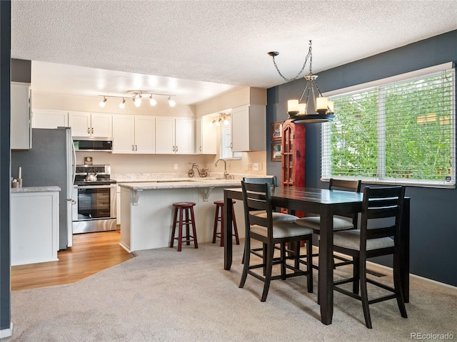 dining space featuring light carpet, a textured ceiling, and an inviting chandelier