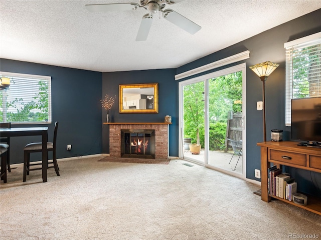 living room featuring carpet floors, a textured ceiling, ceiling fan, and a brick fireplace