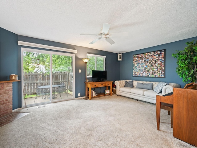 carpeted living room featuring a textured ceiling, ceiling fan, and a brick fireplace