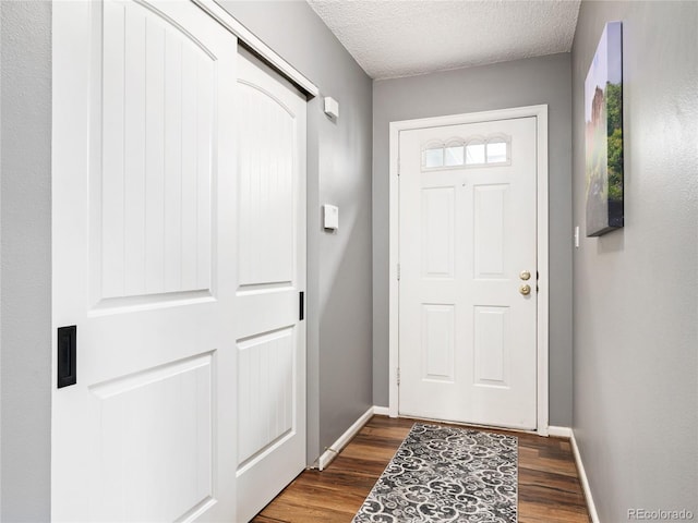 doorway to outside featuring a textured ceiling and dark wood-type flooring