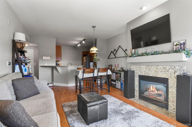 living area with wood finished floors, baseboards, and a tile fireplace