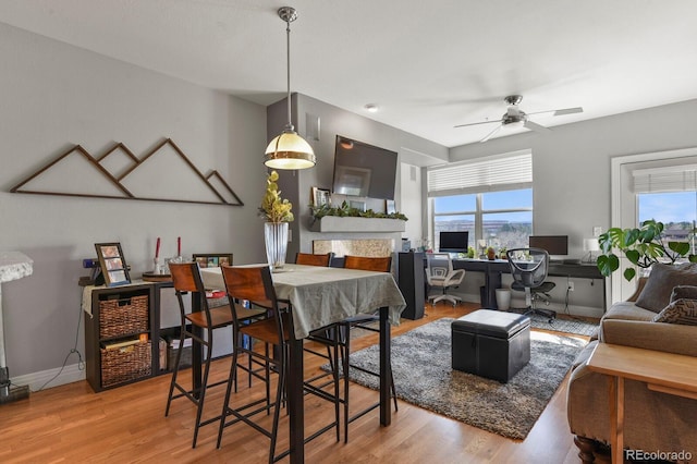 dining room with baseboards, light wood-style floors, a healthy amount of sunlight, and a ceiling fan