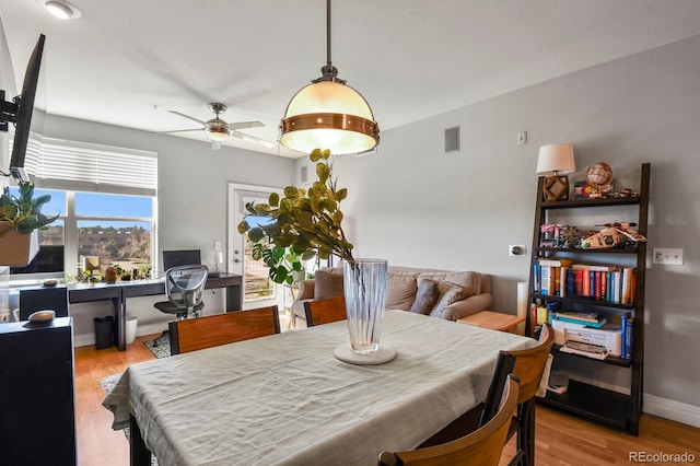 dining space with visible vents, baseboards, wood finished floors, and a ceiling fan