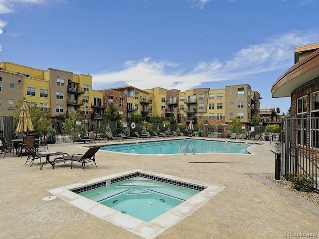 community pool featuring a hot tub, a patio, and fence