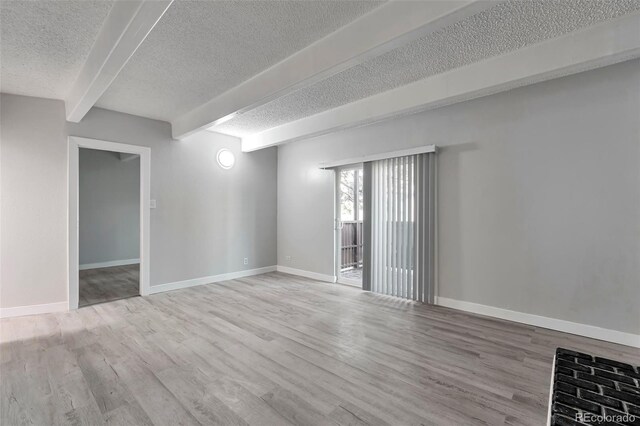 spare room featuring beamed ceiling, a textured ceiling, and hardwood / wood-style flooring